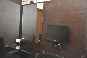 a flat screen tv on a wall with a mirror at City Home in Chennai