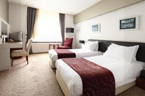 a hotel room with two beds and a desk at Surmeli Istanbul Hotel in Istanbul
