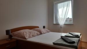 a bed with two pillows on it with a window at Zagi in Povljana