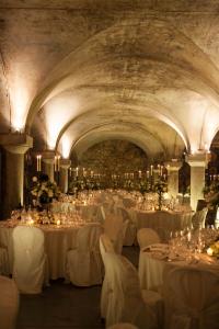 um salão de banquetes com mesas brancas e cadeiras com velas em Albergo l'Ostelliere - Villa Sparina Resort em Gavi