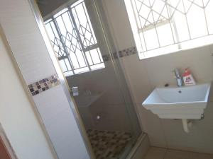 a bathroom with a shower and a sink at Kingdoms Place Guesthouse in Ga-Luka