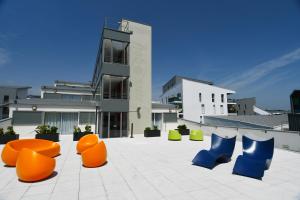 um grupo de cadeiras laranja e azul em frente a um edifício em Appart-Hôtel Mer & Golf City Bordeaux Bassins à flot em Bordeaux