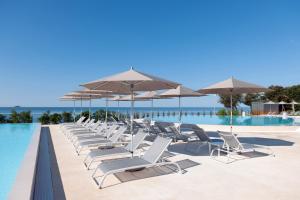 a row of lounge chairs and umbrellas on a swimming pool at Maistra Camping Amarin Mobile homes in Rovinj