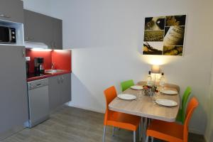 a kitchen with a wooden table with chairs and a kitchen with a refrigerator at Appart-Hôtel Mer & Golf City Bordeaux Bassins à flot in Bordeaux