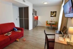 a living room with a red couch and a table at Appart-Hôtel Mer & Golf City Bordeaux Bassins à flot in Bordeaux