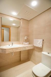 ein Badezimmer mit einem Waschbecken, einem WC und einem Spiegel in der Unterkunft Hotel Santa Maria Playa in Cala Millor
