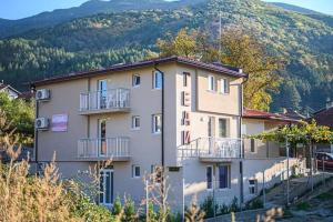 un edificio en una colina con una montaña en Guest house Tedi en Sapareva Banya