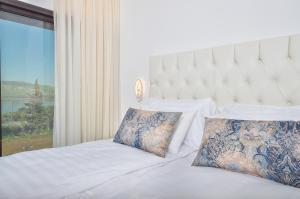 a bedroom with a white bed with a large window at פרימור סוויטות יוקרה Primor Deluxe Suits in Kinneret