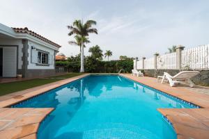 een zwembad met blauw water voor een huis bij Villa Cosmos chalet con gran piscina y jardin privado in Maspalomas