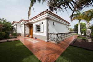 een klein wit huis met een palmboom bij Villa Cosmos chalet con gran piscina y jardin privado in Maspalomas