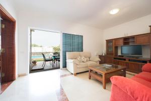 een woonkamer met een bank en een tv bij Villa Cosmos chalet con gran piscina y jardin privado in Maspalomas