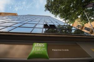 un cartello di fronte a un edificio di vetro di Ibis Styles Palermo Cristal a Palermo