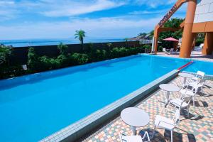 a swimming pool with tables and chairs next to the ocean at Boyokaku in Amakusa