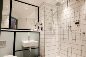 
a bathroom with a shower, sink, and mirror at The Fox & Goose Hotel in London
