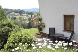eine Terrasse mit einem Tisch, Stühlen und Blumen in der Unterkunft Ferienhof Scholz in Spiegelau