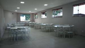 a dining room with tables and chairs and windows at Pousada Montanhas do Caparaó in Caparaó Velho