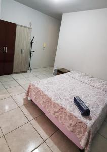 a bedroom with a bed with a remote control on it at Apto Jk em Cachoeirinha in Cachoeirinha