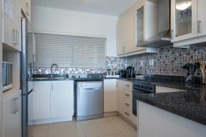 a kitchen with white appliances and black counter tops at Pebble Beach 1 in Ballito