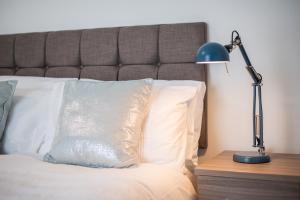 a bed with a white pillow and a blue lamp at Spacious 4BR Home with Garden, Swansea in Swansea +36 photos