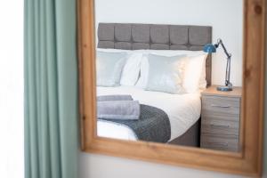 a mirror reflecting a bedroom with a bed and a chair at Spacious 4BR Home with Garden, Swansea in Swansea
