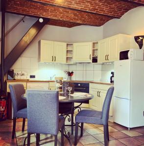 eine Küche mit einem Tisch und Stühlen sowie einem weißen Kühlschrank in der Unterkunft Gite de La Belle Etable in Falmignoul