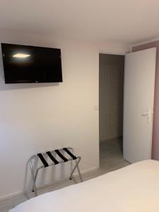 1 dormitorio con TV en la pared y silla en Aix Hotel, en Aix-en-Provence