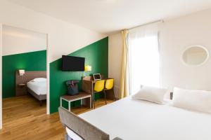 1 dormitorio con cama blanca y pared verde en Aparthotel Adagio Access Carrières Sous Poissy en Carrières-sous-Poissy