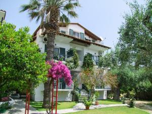 una casa con una palma e fiori di fronte di Giovanni Group Apartments a Sivota