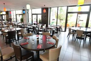 a dining room with tables and chairs and windows at Appart-Hôtel Mer & Golf City Bordeaux - Bruges in Bruges