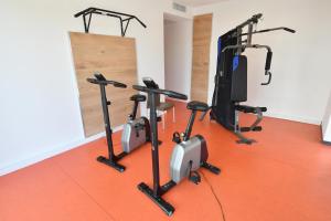 - une salle de sport avec plusieurs vélos d'exercice et un tapis de course dans l'établissement Appart-Hôtel Mer & Golf City Bordeaux - Bruges, à Bruges