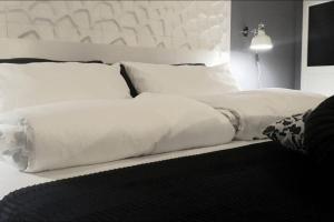 ein Bett mit weißer Bettwäsche und Kissen darauf in der Unterkunft JOIVY Heart of the City 1 Bed Apt near Castle Belvedere in Genua