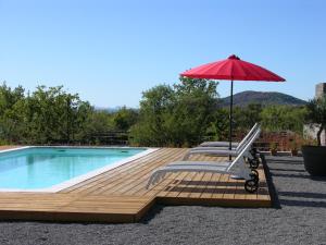 una terrazza con sedia e ombrellone accanto alla piscina di 3Houses N°1 a Lagorce