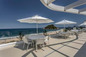 CDesign Hotel في ريو دي جانيرو: صف من الطاولات والكراسي مع مظلات على الشاطئ
