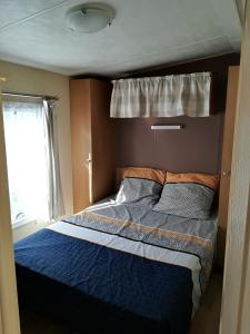 a bedroom with a bed with a blue comforter and a window at Camping la Palmyre in Les Mathes