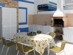 eine Küche mit einem Tisch mit Stühlen und einem Tischtuch in der Unterkunft Vivenda Carioca in Vila Nova De Cacela