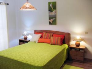 ein Schlafzimmer mit einem grünen Bett mit zwei Nachttischen in der Unterkunft Vivenda Carioca in Vila Nova De Cacela