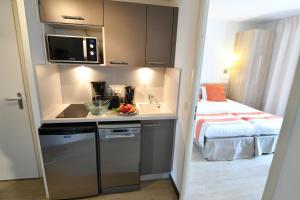 a small kitchen with a sink and a bed in a room at Appart-Hôtel Mer & Golf City Bordeaux - Bruges in Bruges