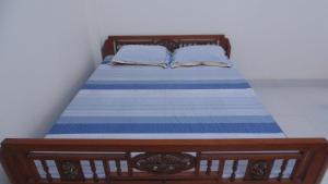 un letto in legno con lenzuola e cuscini blu e bianchi di Homestay Nam Dong a Hanoi