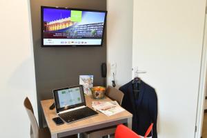 a laptop on a table with a tv on the wall at Appart-Hôtel Mer & Golf City Bordeaux - Bruges in Bruges