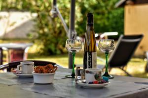 una botella de vino sentada en una mesa con copas en Hôtel Deybach, en Munster