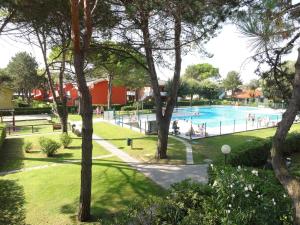 a large swimming pool in a park with trees at Villaggio Azzurro - Ville in Bibione