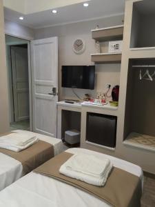 Cette chambre comprend deux lits, un bureau et une télévision. dans l'établissement Guesthouse Luisella, à Cagliari