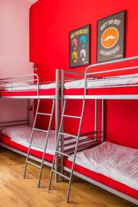 2 Etagenbetten in einem Zimmer mit roten Wänden in der Unterkunft Retro Hostel in Posen
