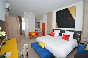 a bedroom with a large white bed with red and yellow pillows at Manoir Henri Giraud & Spa in Épernay