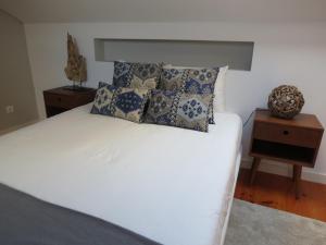 um quarto com uma cama branca com almofadas e uma mesa de cabeceira em Belém 25, duplex apartment em Lisboa