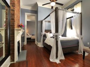 a bedroom with a canopy bed and a fireplace at Luxury Historic Shotgun Home in Lower Garden District in New Orleans