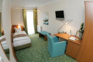 a hotel room with a bedroom with a bed and a desk at Isselhorster Landhaus in Gütersloh