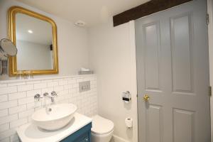 a bathroom with a toilet, sink, and mirror at Mercure Barnsley Tankersley Manor Hotel in Barnsley