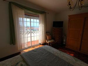 ein Schlafzimmer mit einem Bett und einem großen Fenster in der Unterkunft Villa Bela Vista near a surf spot in Ericeira