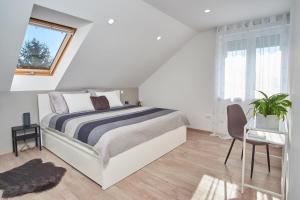 a white bedroom with a bed and a window at Apartman Rafi in Čakovec